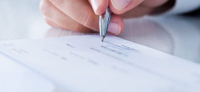 a person holding a pen over a piece of paper.