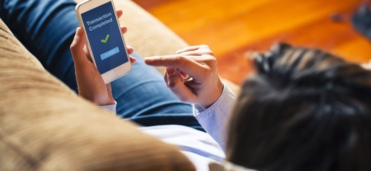 a woman sitting on a couch holding a smart phone.