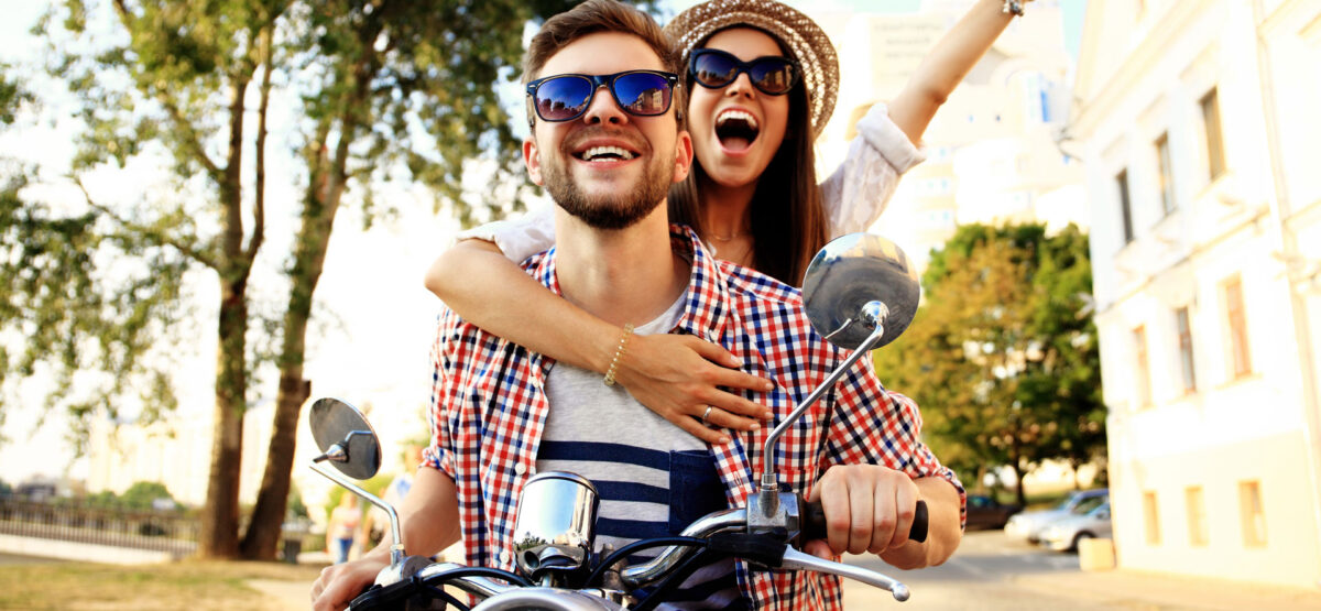 a man and a woman riding on the back of a scooter.