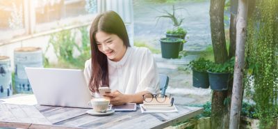 a woman sitting at a table using a laptop computer.