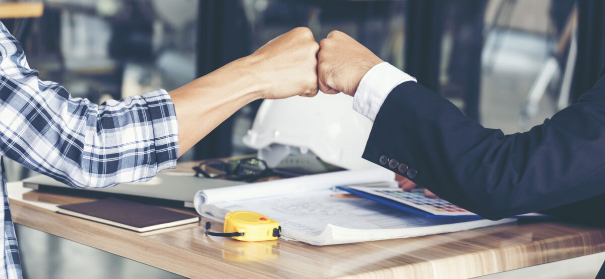 a man and a woman fist bumping hands at a table.