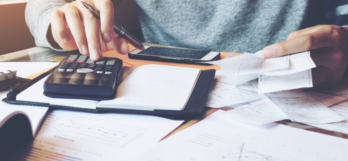 a person sitting at a desk with a calculator.