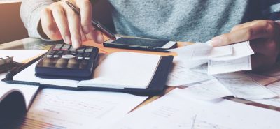 a person sitting at a desk with a calculator.